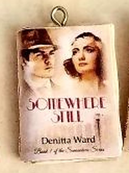 Close-up of one finished Somewhere Still mini-book charm with its metal screw eye