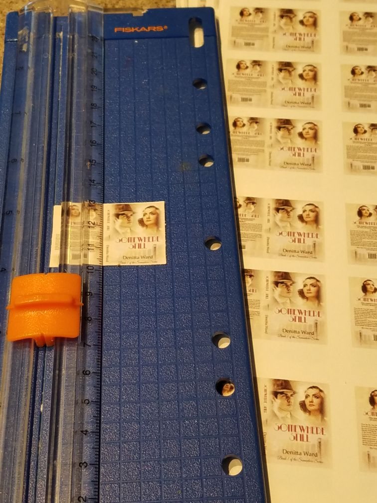 A printed sheet of mini covers being trimmed on a paper cutter