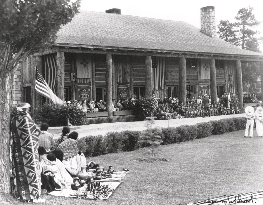 Historic photograph of Fuller Lodge, Los Alamos, with people seated on the lawn